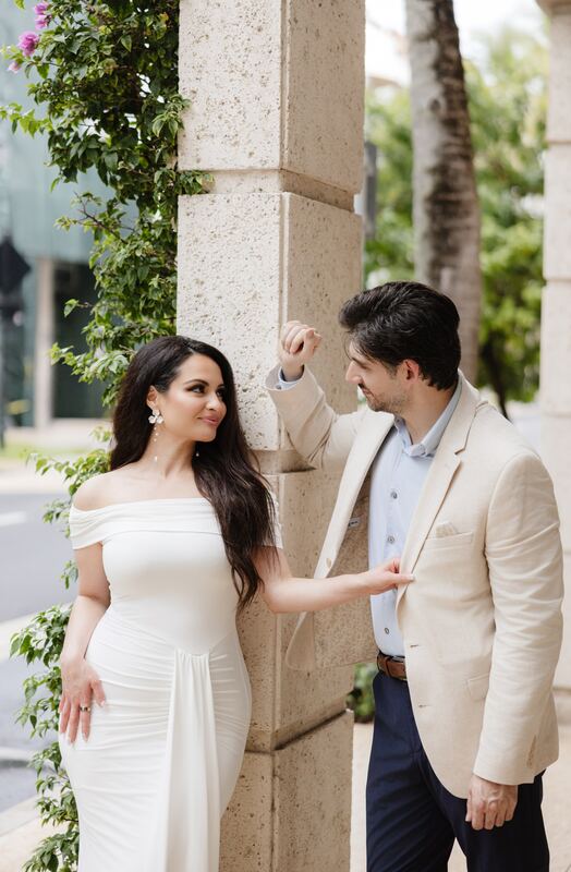 Iviani reaching for Joey&rsquo;s hand beside a vine-covered column