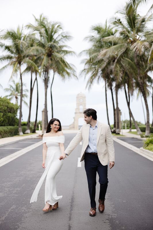 Iviani and Joey walking hand in hand down a palm-lined avenue