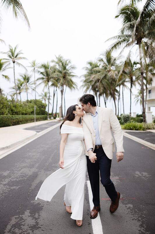 Iviani and Joey kissing on a palm-lined avenue