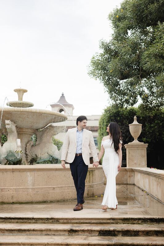 Iviani and Joey walking hand in hand past the fountain