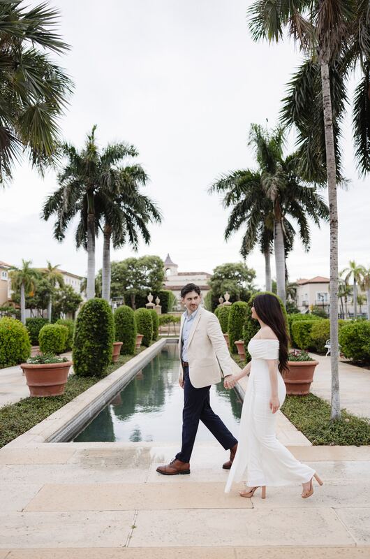 Iviani and Joey strolling along the reflecting pool under royal palms