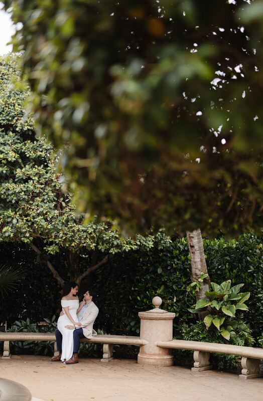 Iviani and Joey on a garden bench, seen through the leaves