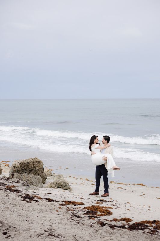 Iviani and Joey embracing on the beach at the water&rsquo;s edge